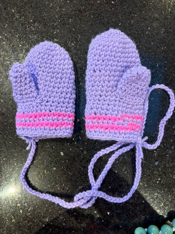 Purple crocheted baby mittens with a pink stripe
