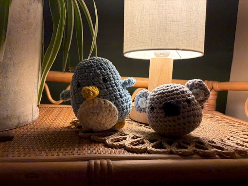 Cute crocheted amigurumi penguin and koala on a table